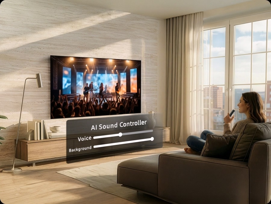 Woman watches musical performance on a Samsung TV. Below it, AI Sound Controller shows volume levels for the audio as two separate tracks: Voice and Background. As she speaks into the remote control ‘I want to hear the singing louder’, it adjusts to increase Voice and reduce Background.