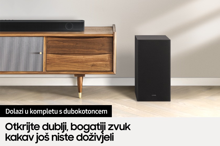 Samsung soundbar zvučnik B550 smješten je na TV ormariću, dok se njegov pripadajući dubokotonac nalazi pokraj ormarića.