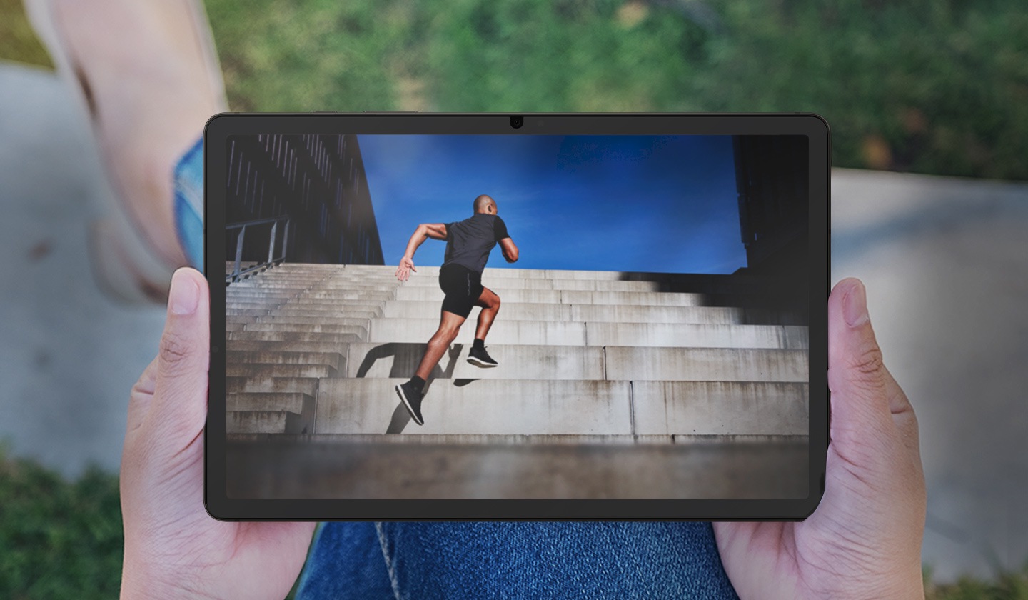 A Galaxy Tab S9 elölről látszik, és egy személy tartja a szabadban, emiatt fénylik és tükröződik a képernyő.