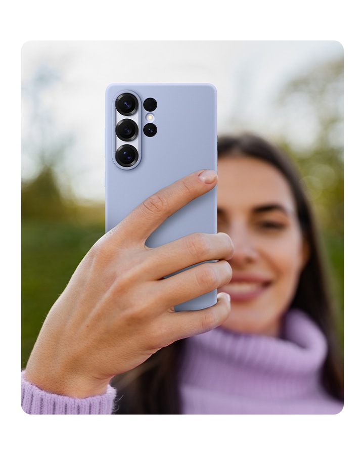 Egy ember egy szürke színű szilikon tokba helyezett Galaxy S25 Ultra telefont tart a kezében.