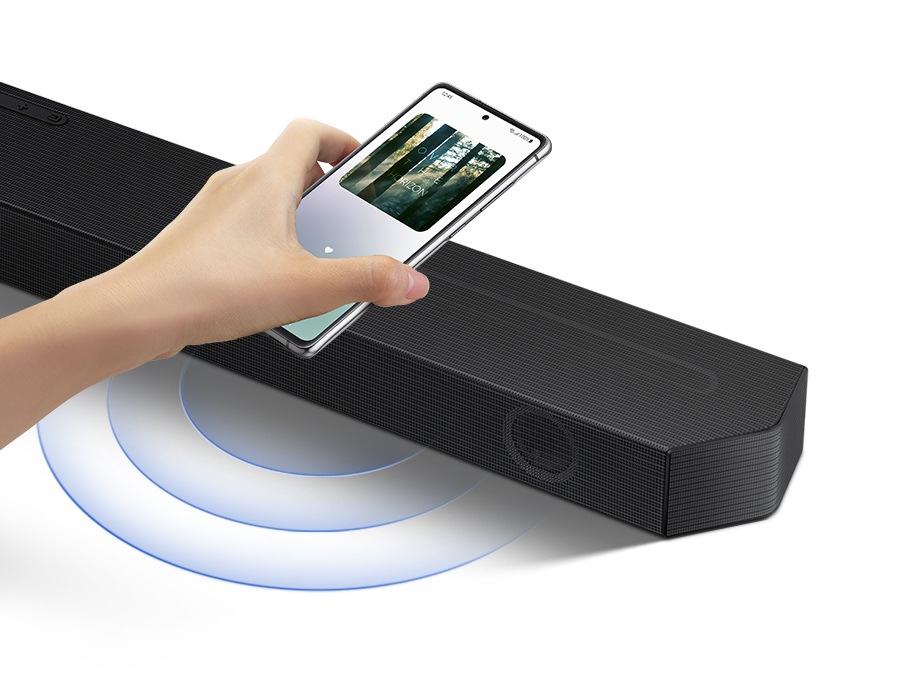 A hand taps a smartphone with the Samsung music app on-screen on the soundbar and the soundbar instantly plays music, showing how easy it is to switch from smartphone to soundbar.