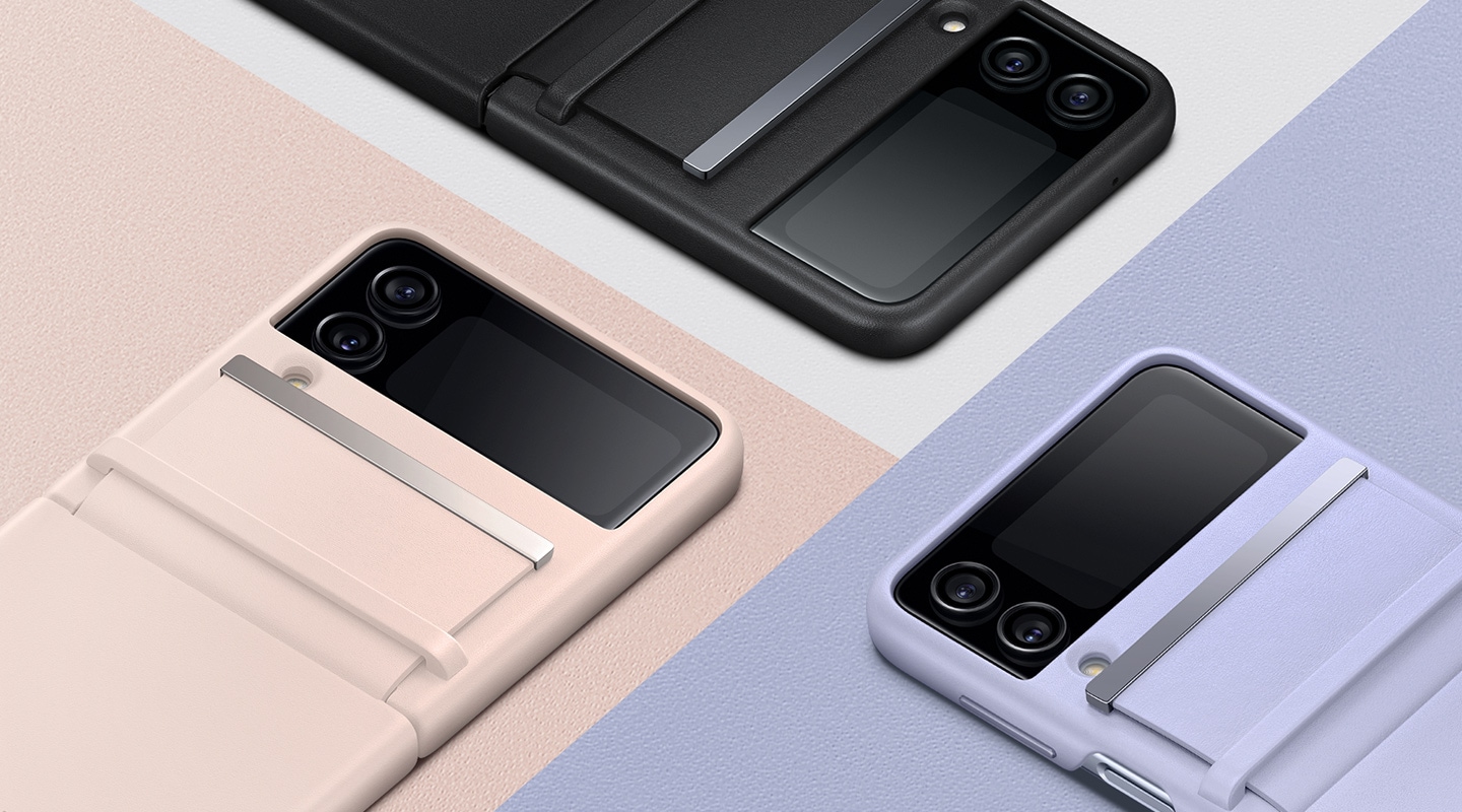 Három Galaxy Z Flip 4 telefon Kihajtható bőrtokban, Rózsaszín, Fekete és Lila színben lefordítva az asztalra van fektetve, olyan alakban, hogy kiemeljenek minden színt.