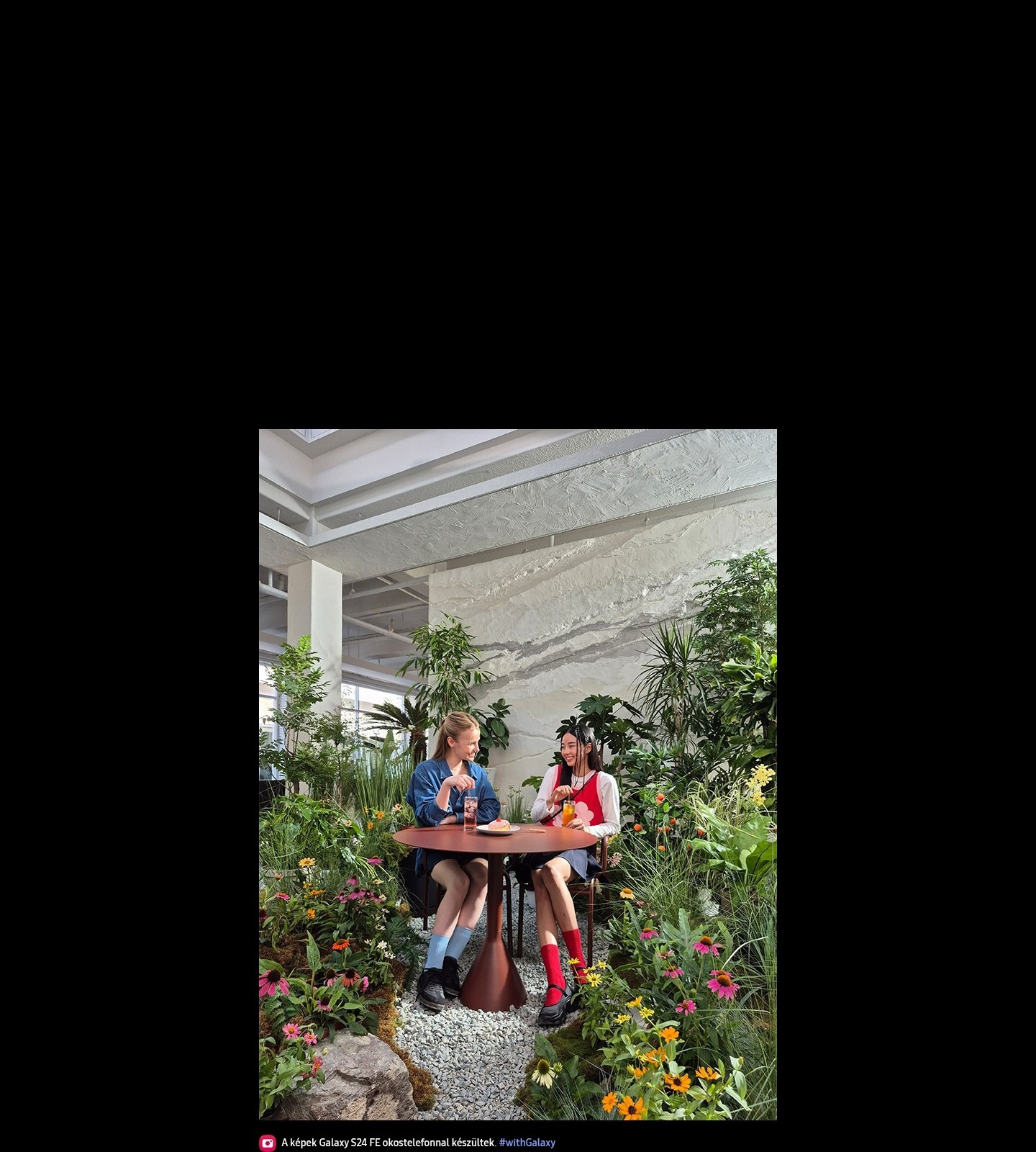 Egy fotó látható két emberről, akik együtt ülnek egy asztalnál, élénk szobanövényekkel és virágokkal körülvéve. A szöveg a következő: A képek Galaxy S24 FE okostelefonnal készültek. #withGalaxy.