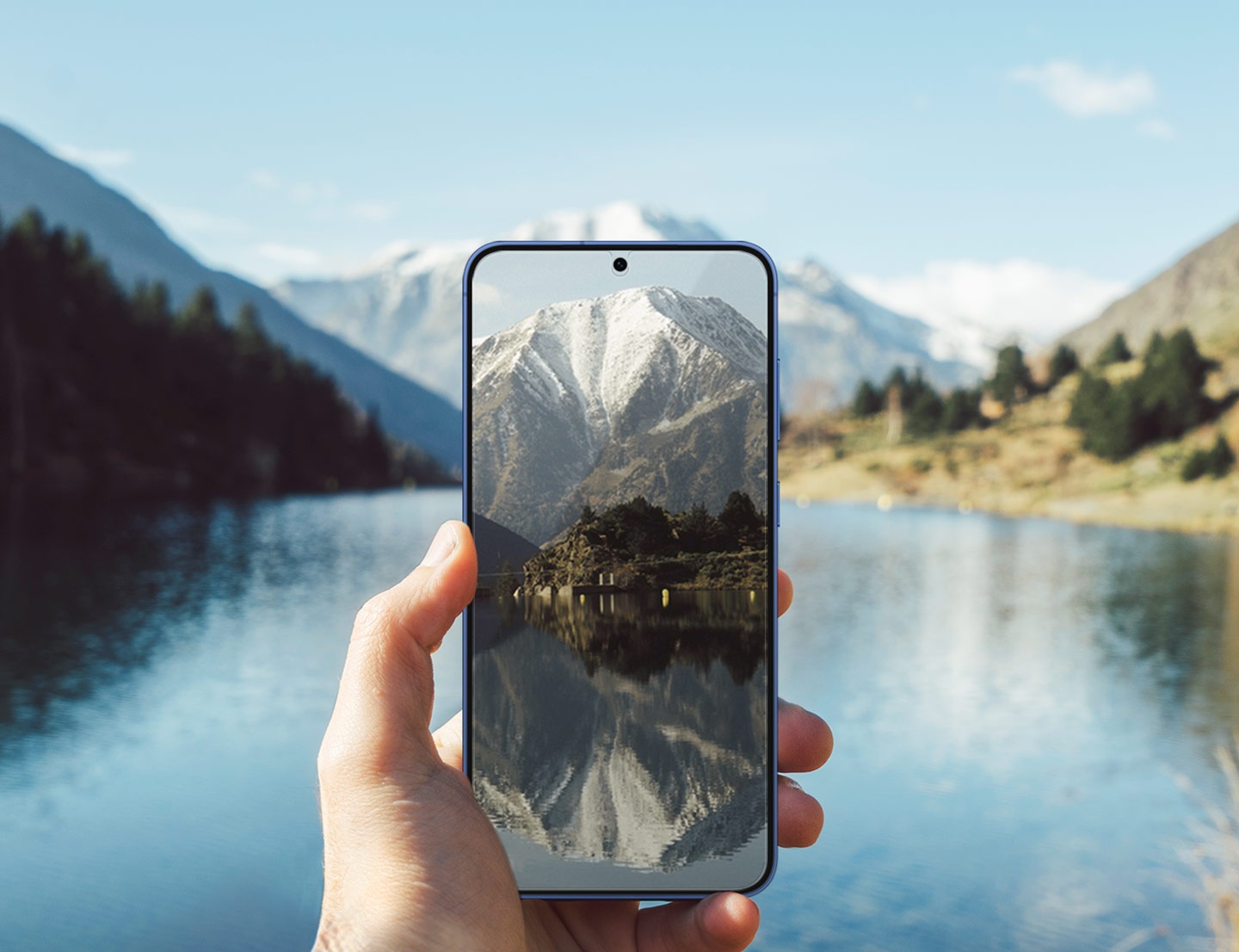 A person holds a Galaxy S25+ with the Anti-reflecting Film installed on its screen. With a lake glimmering in the backdrop, the phone's display remains clear visibility.