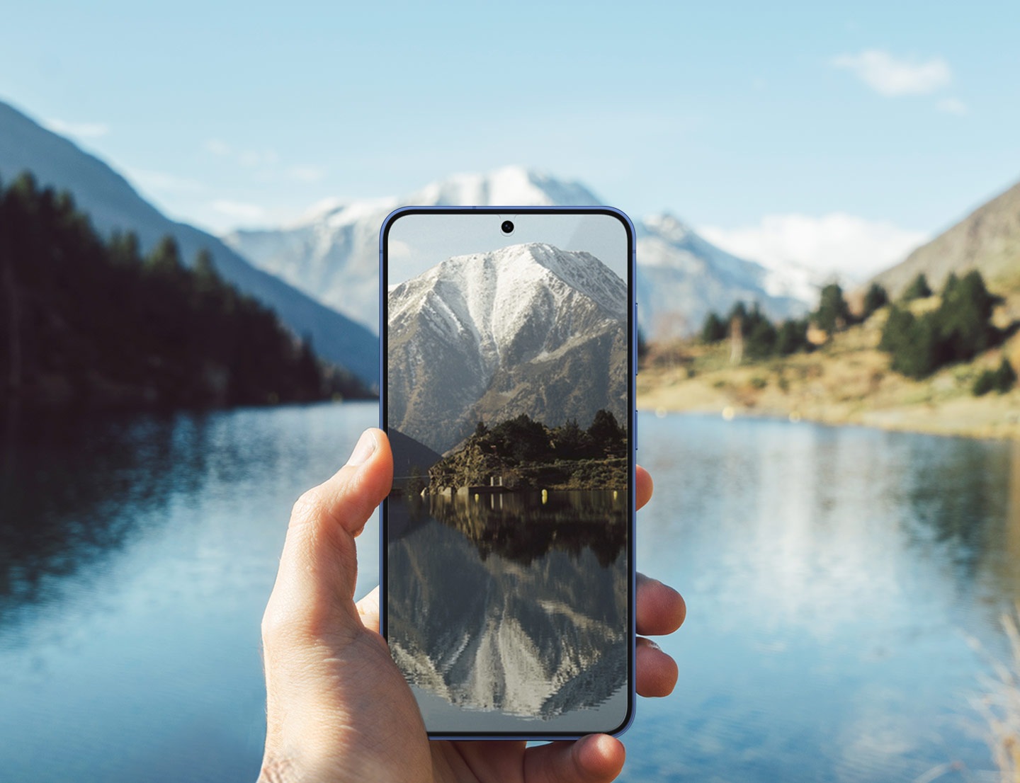 A person holds a Galaxy S25 with the Anti-reflecting Film installed on its screen. With a lake glimmering in the backdrop, the phone's display remains clear visibility.