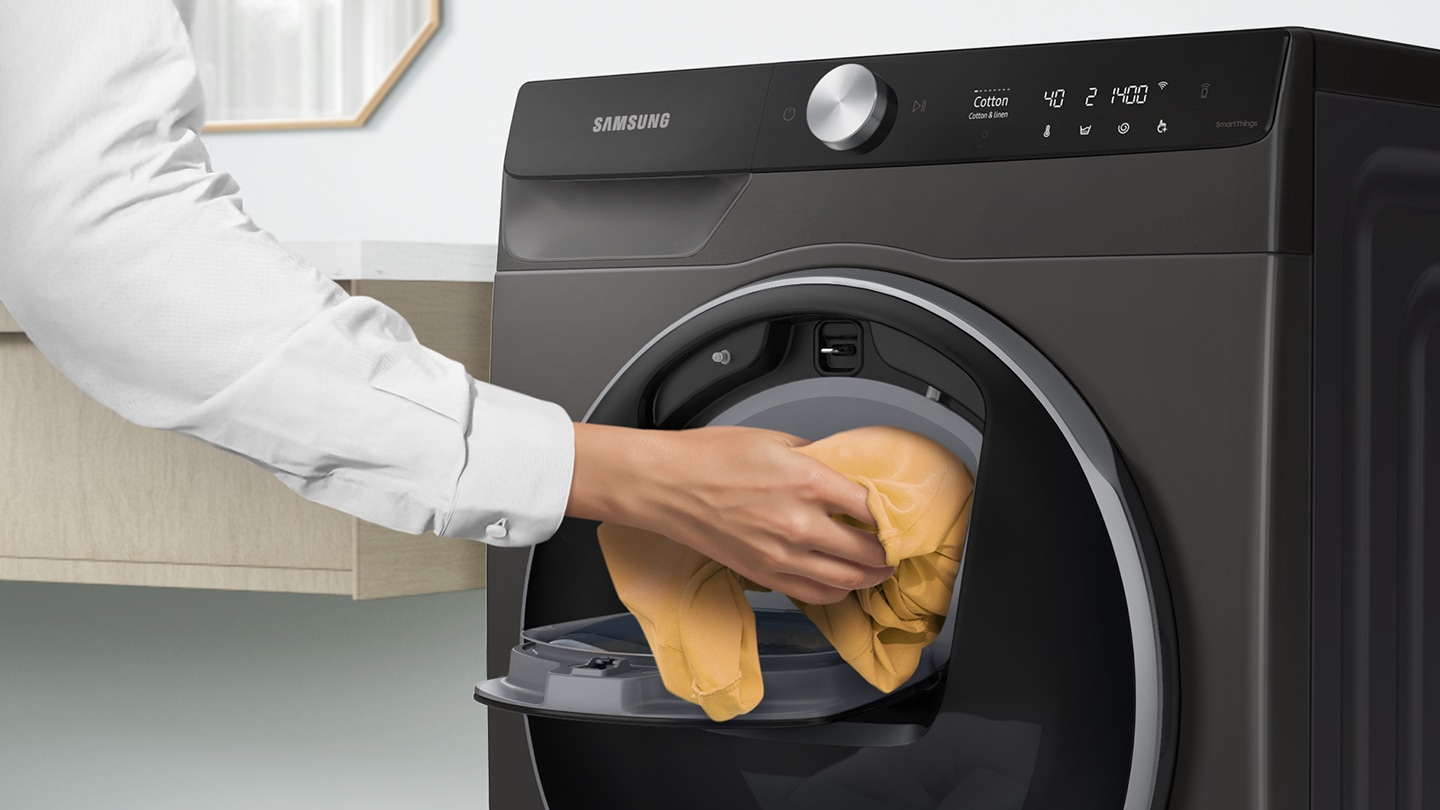 Extra laundry is added into the open Add Wash door by hand.