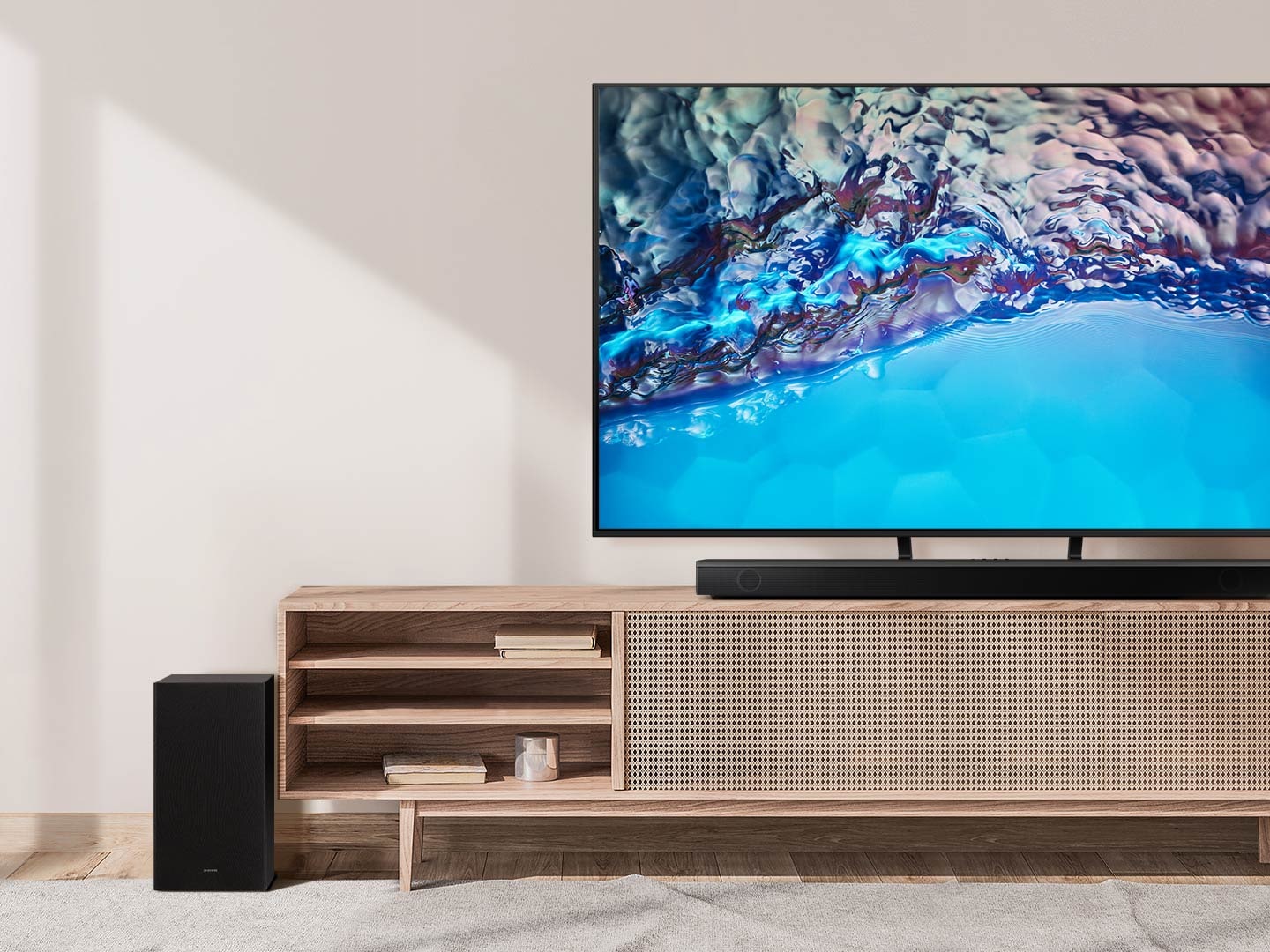 Samsung B series Soundbar and subwoofer are positioned with Crystal UHD TV on living room cabinet.