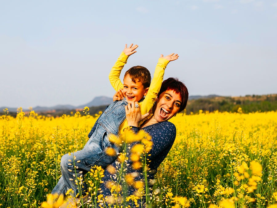A shot of a mother holding her young son in a field of yellow flowers in vivid clear colors
