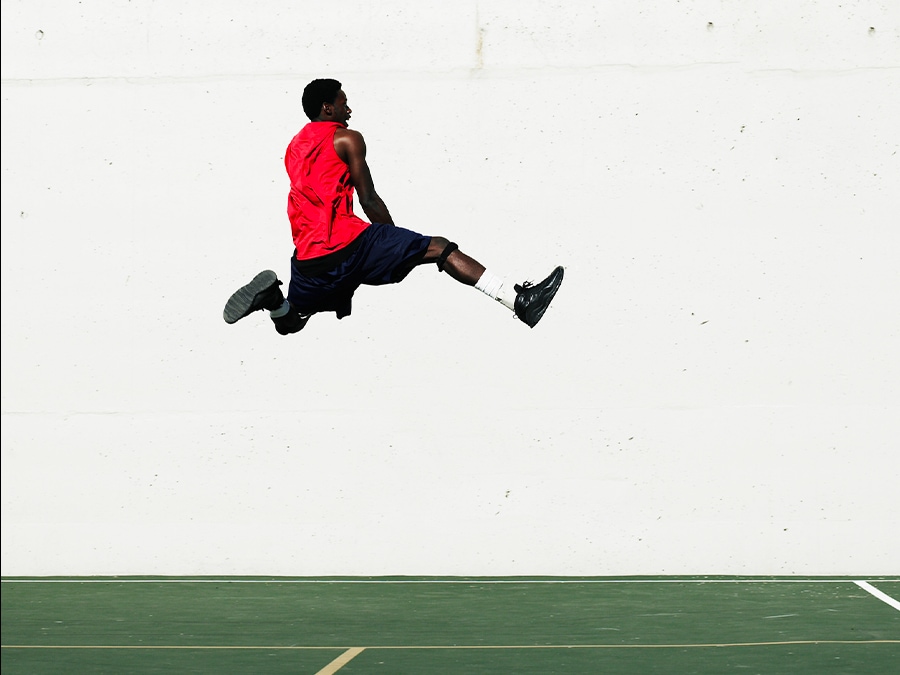 A shot of a man jumping in front of a white wall with his shadow erased.