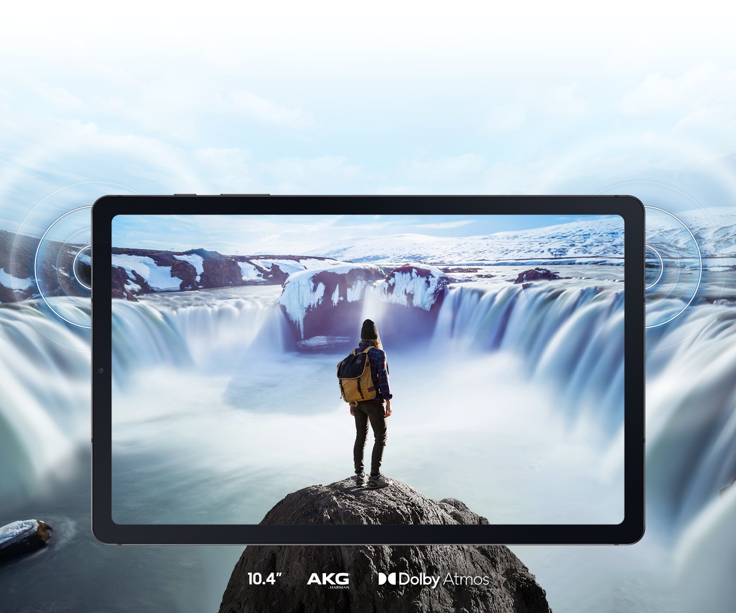 An image of a backpacker standing on a cliff in front of a waterfall is shown on a Galaxy Tab S6 Lite device in landscape orientation. The picture extends outside of the device's screen in all directions to highlight the immersive experience from the small-bezel screen and dual speakers. The AKG and Dolby Atmos logos are displayed.