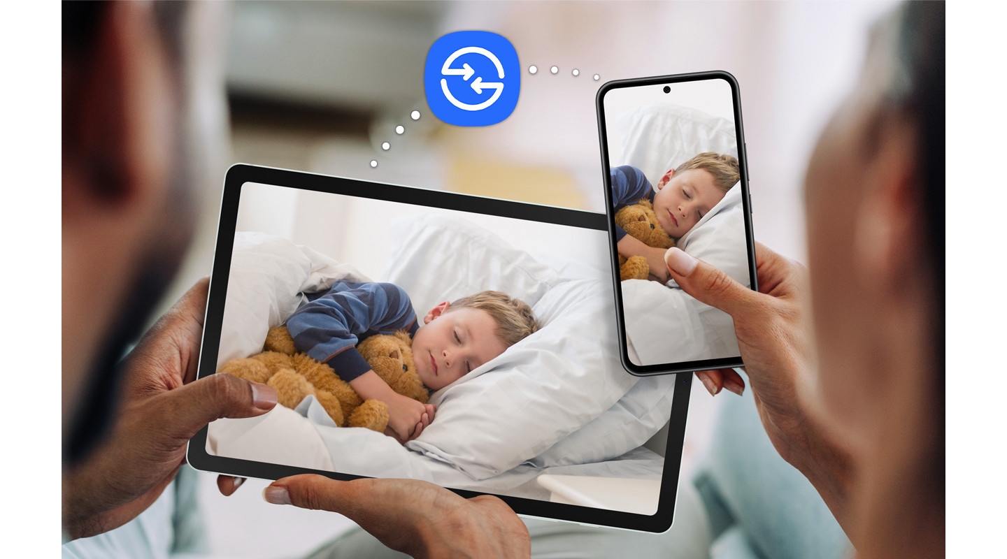 A couple is holding up Galaxy Tab S6 Lite and a Galaxy smartphone, both with the same photograph of a sleeping child onscreen. The Quick Share icon in the middle to indicate the file-sharing feature.