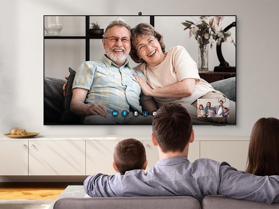 A family of four are video calling with grandparents via the TV.
