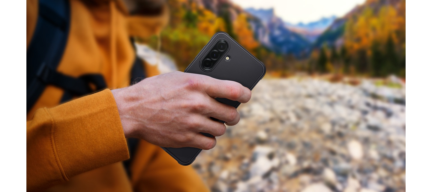 A close-up of a person holding Galaxy A36 5G in the Rugged Case while trekking outdoors.