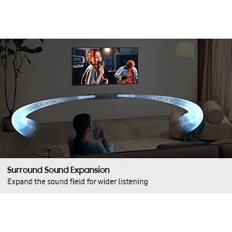 A woman watches TV in a living room. Sound waves shoot out from the soundbar and travel in various directions to surround her.