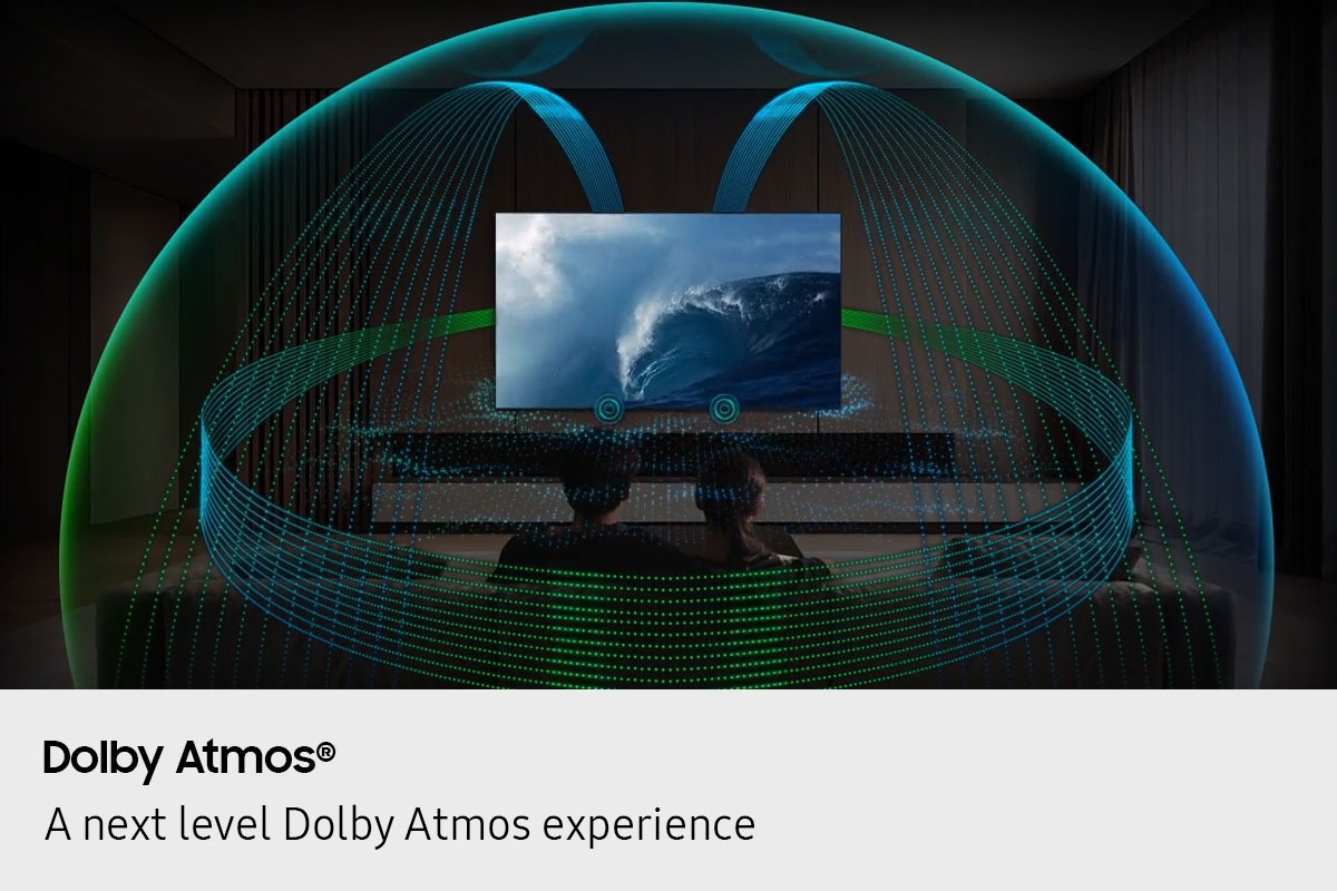 In a living room, a couple sits on a sofa and watches TV. The TV’s front speakers are lit up and soundwaves emanate from a TV’s speakers, travelling in multiple directions to surround the couple in a dome of sound and fill the room. Dolby Atmos logo.