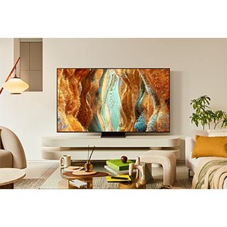 In a cluttered living room, a Samsung Neo QLED TV displays a grassy fantasy landscape on screen.