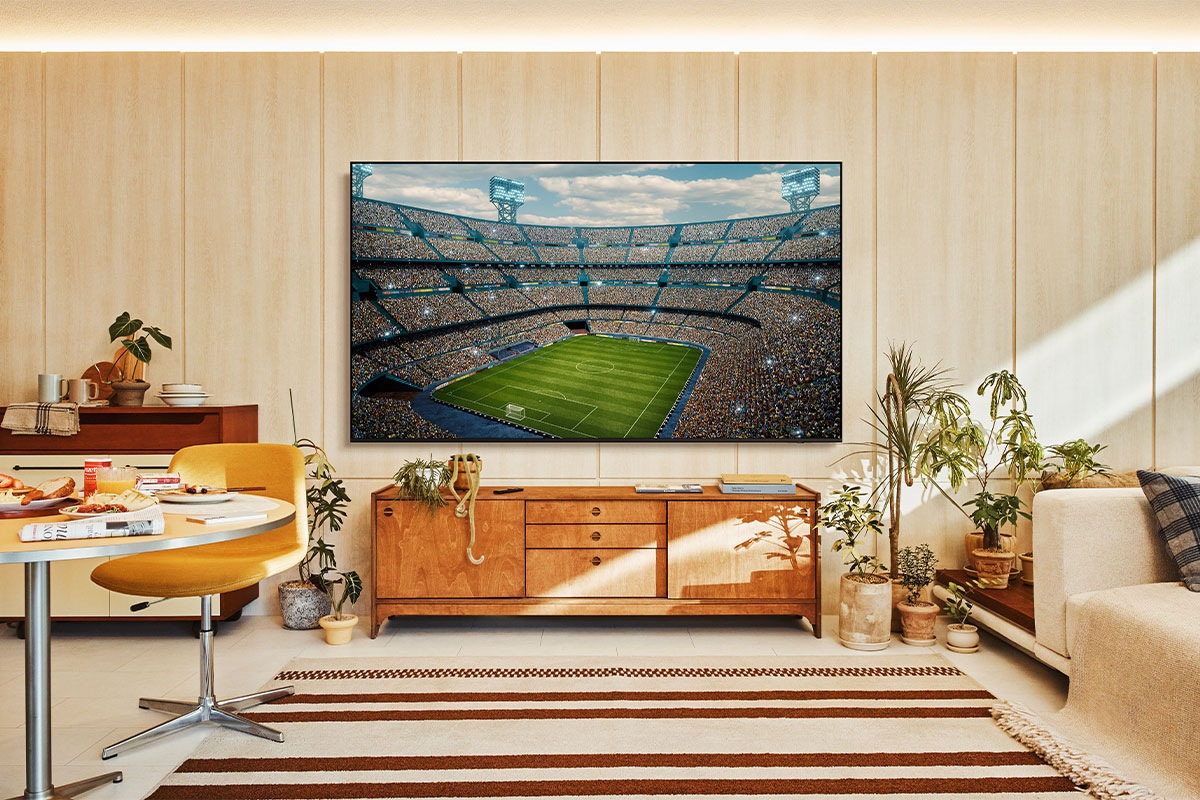 A U8500F is installed on the wall of a living room. It depicts a scene of a crowded stadium in vivid colors.