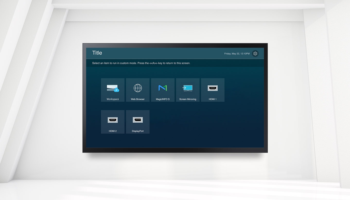 There is a custom home function screen in the QMB-T. Title is written on the upper left, the day and time are written on the upper right, and there is a setting icon next to it. Select an item to run in custom mode. Workspace, Web Browser, MagicINFO S, Screen Mirroring, HDMI 1, HDMI 2, DisplayPort features are listed with the text Press the <