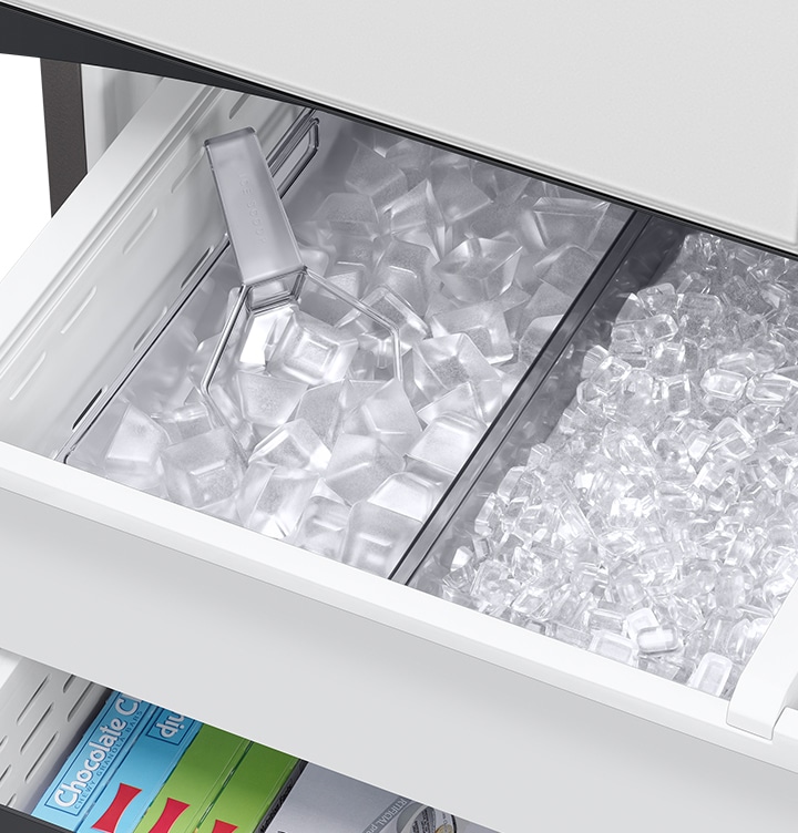 The dual tray in the freezer is full of ice. The left tray is full of large ice cubes and the right tray is full of small ice cubes.