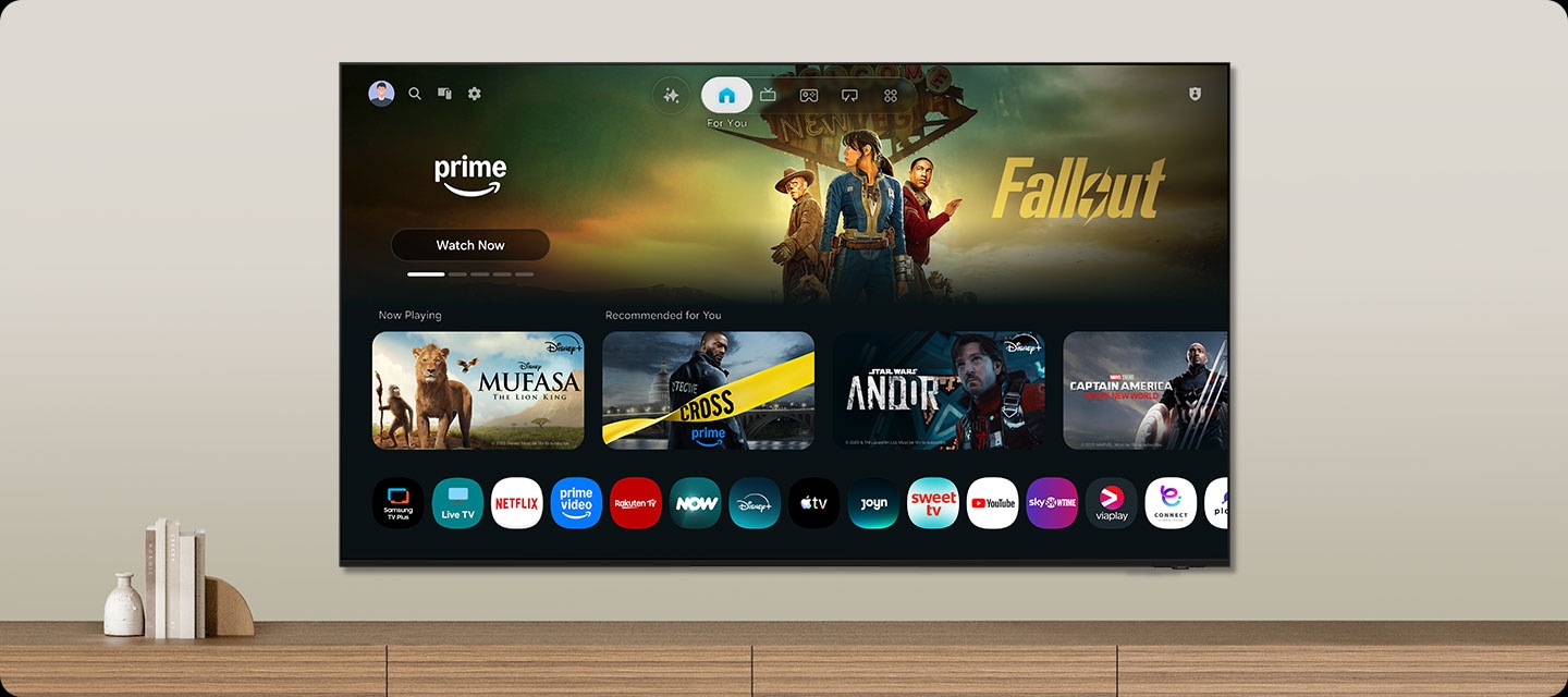 One UI Tizen’s home screen, with the various apps and services available, is displayed on a TV in a living room.