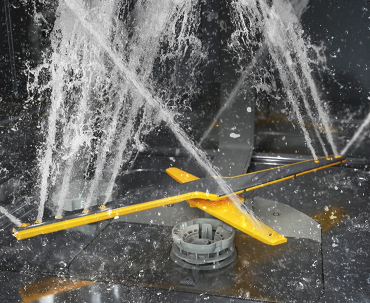 Shows the rotating dual wash arms of the WaterJet Clean&trade; system spraying powerful jets of water in multiple directions.