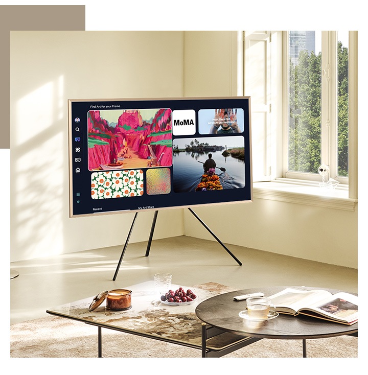טלוויזיית The Frame על Studio Stand בסלון מציגה את מסך Art Home עם כמה מיצירות האומנות הזמינות ב-Art Home.