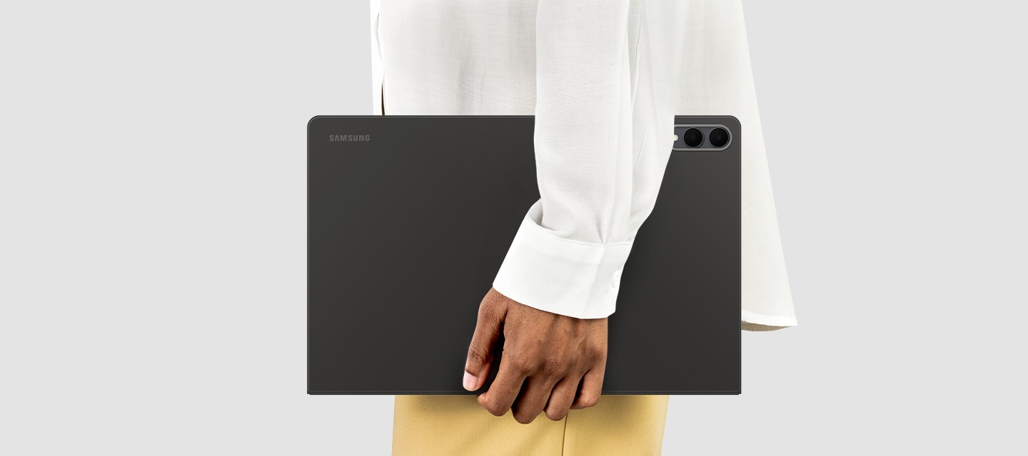 Side view of a person holding Galaxy Tab S11 Ultra with Book Cover on, showing its slim profile and lightweight form that is easy to carry for everyday use on the go.