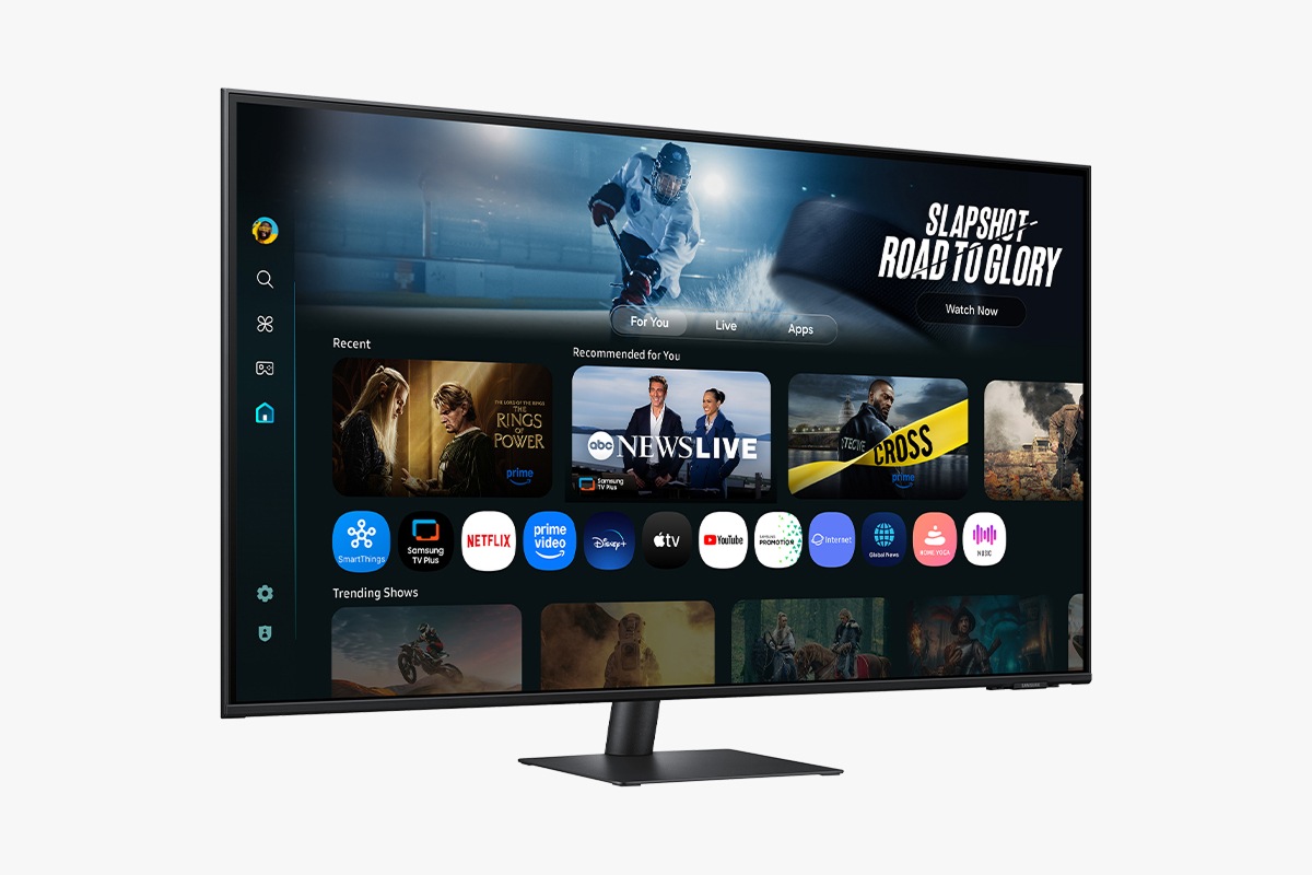 Front-left perspective of 43 inch Samsung Smart Monitor M7. Screen showing Smart TV Apps page with various content and apps lined up.