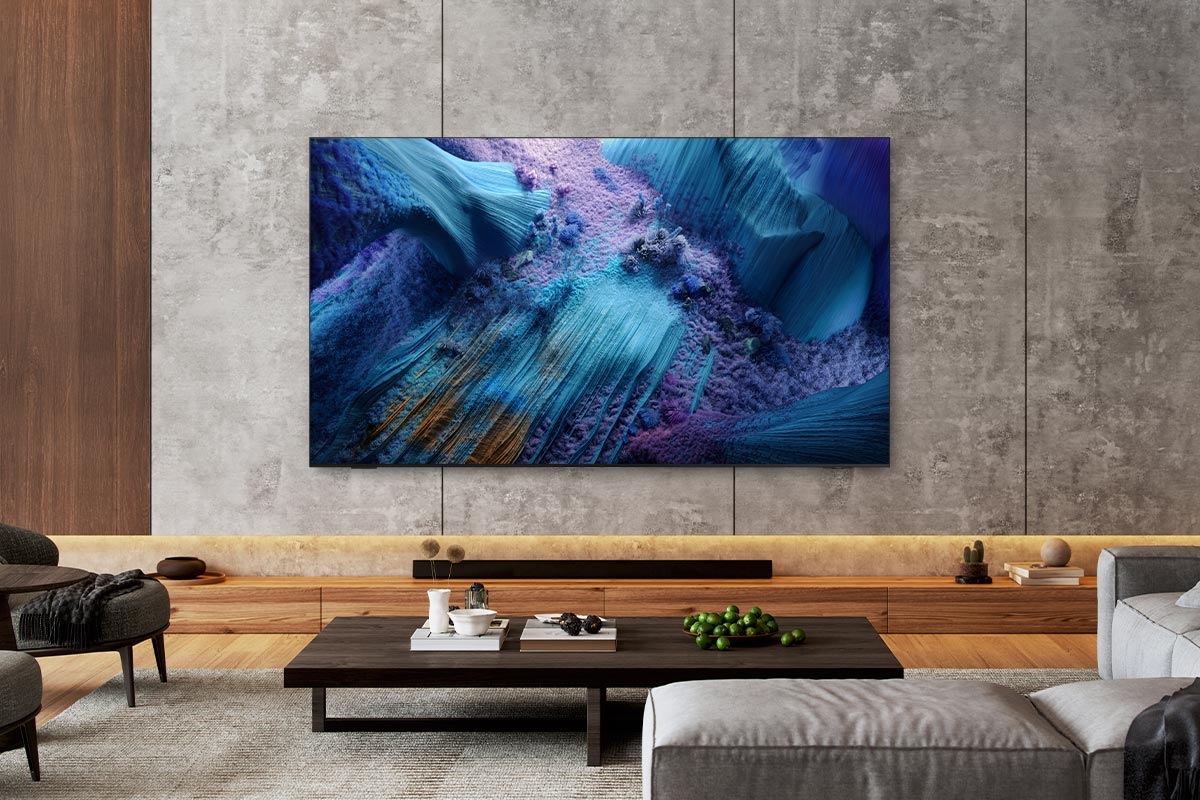 A Neo QLED TV is installed on the wall of a modern living room. The screen displays a blue abstract landscape.