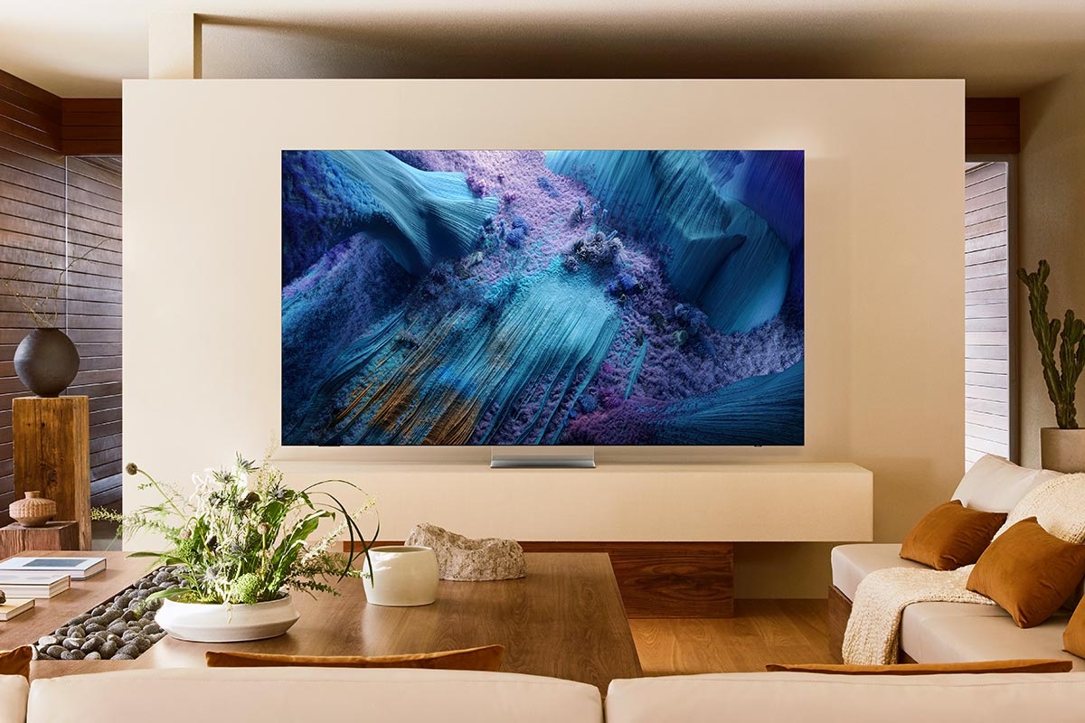 A Neo QLED TV is set on a stand in a living room. It displays a blue abstract landscape on screen.