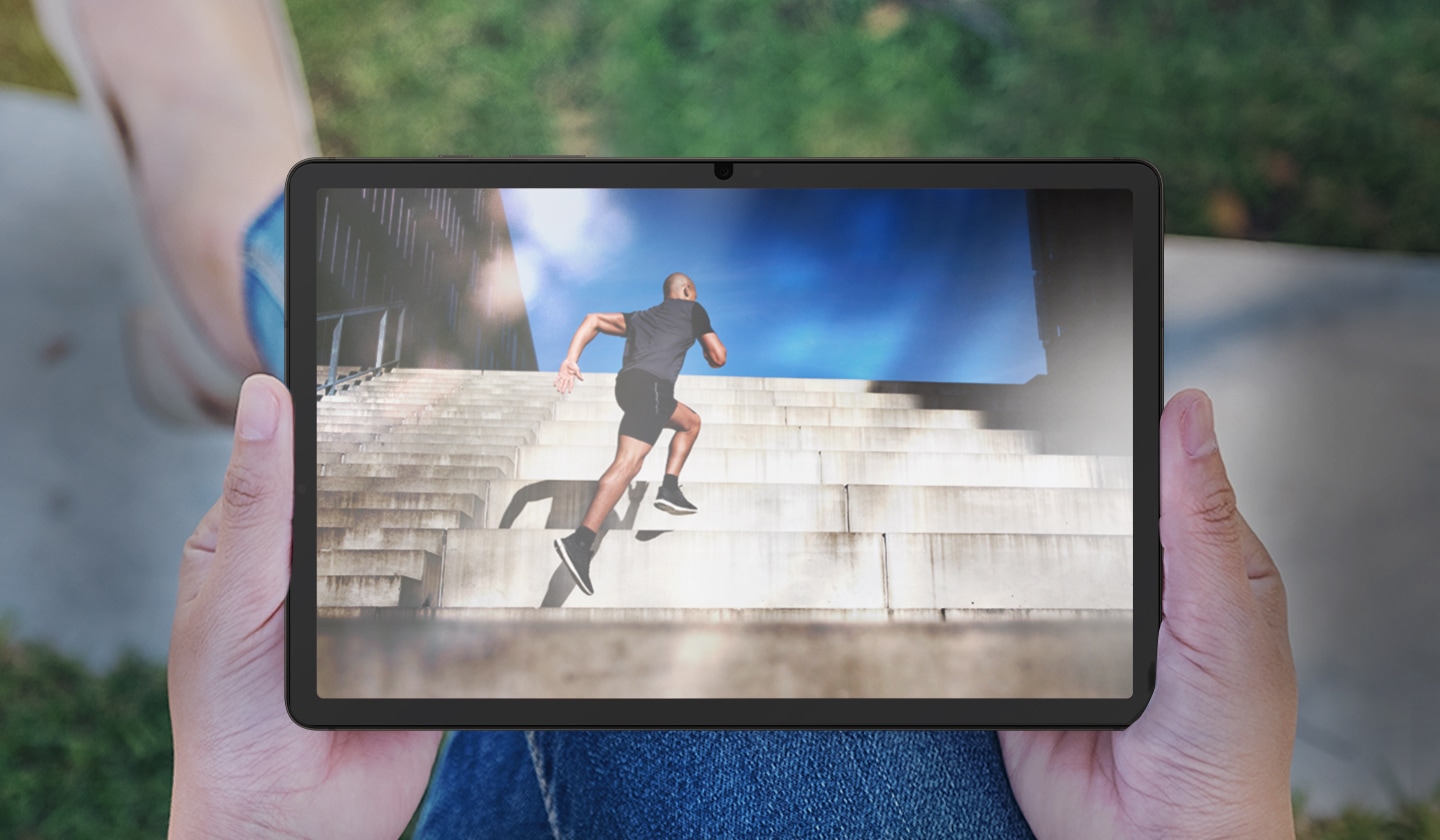 A front view of Galaxy Tab S9, held by a person outdoors, with glare and reflection seen on the screen.