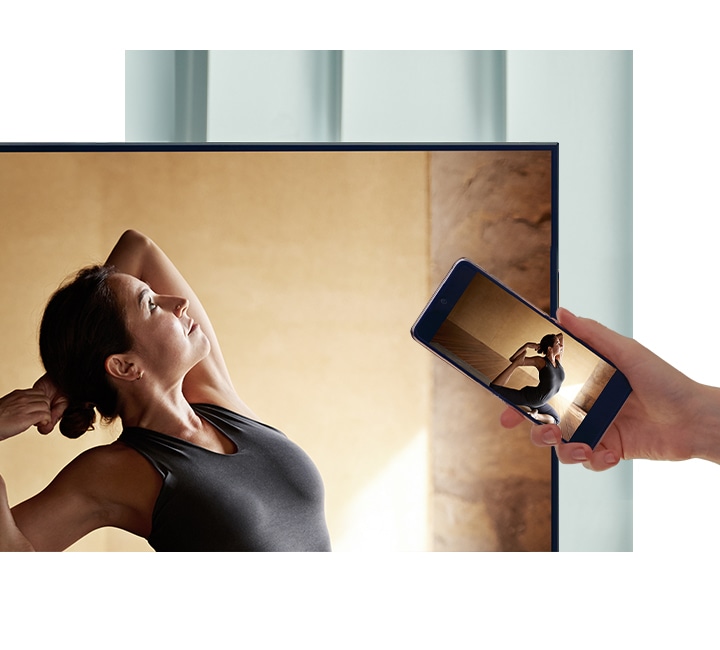 Un utilisateur place son smartphone contre son téléviseur AU7000 pour refléter le contenu de sa ballerine sur un écran plus grand pour plus de confort.