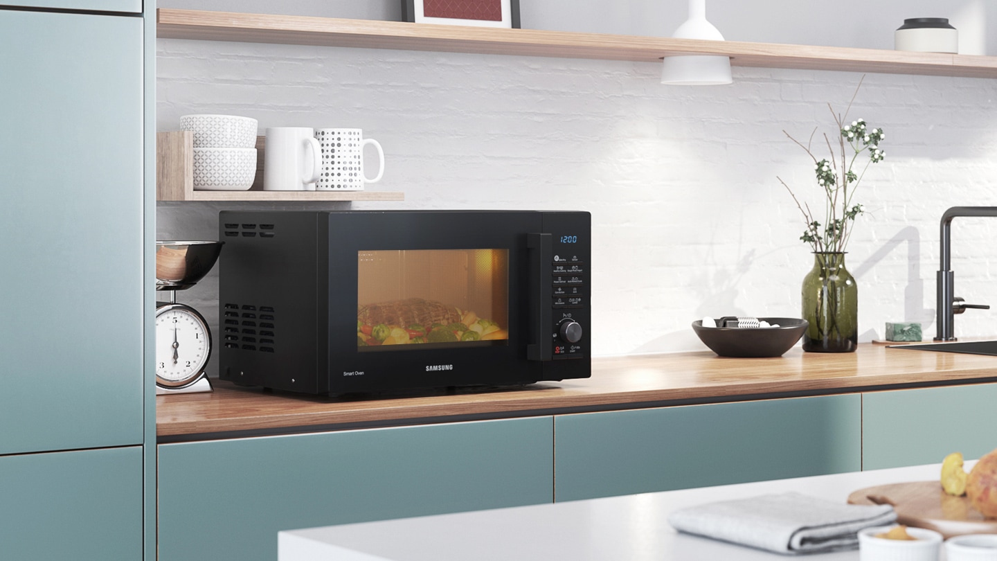 shows the microwave oven on a kitchen worktop, surrounded by various kitchenware.