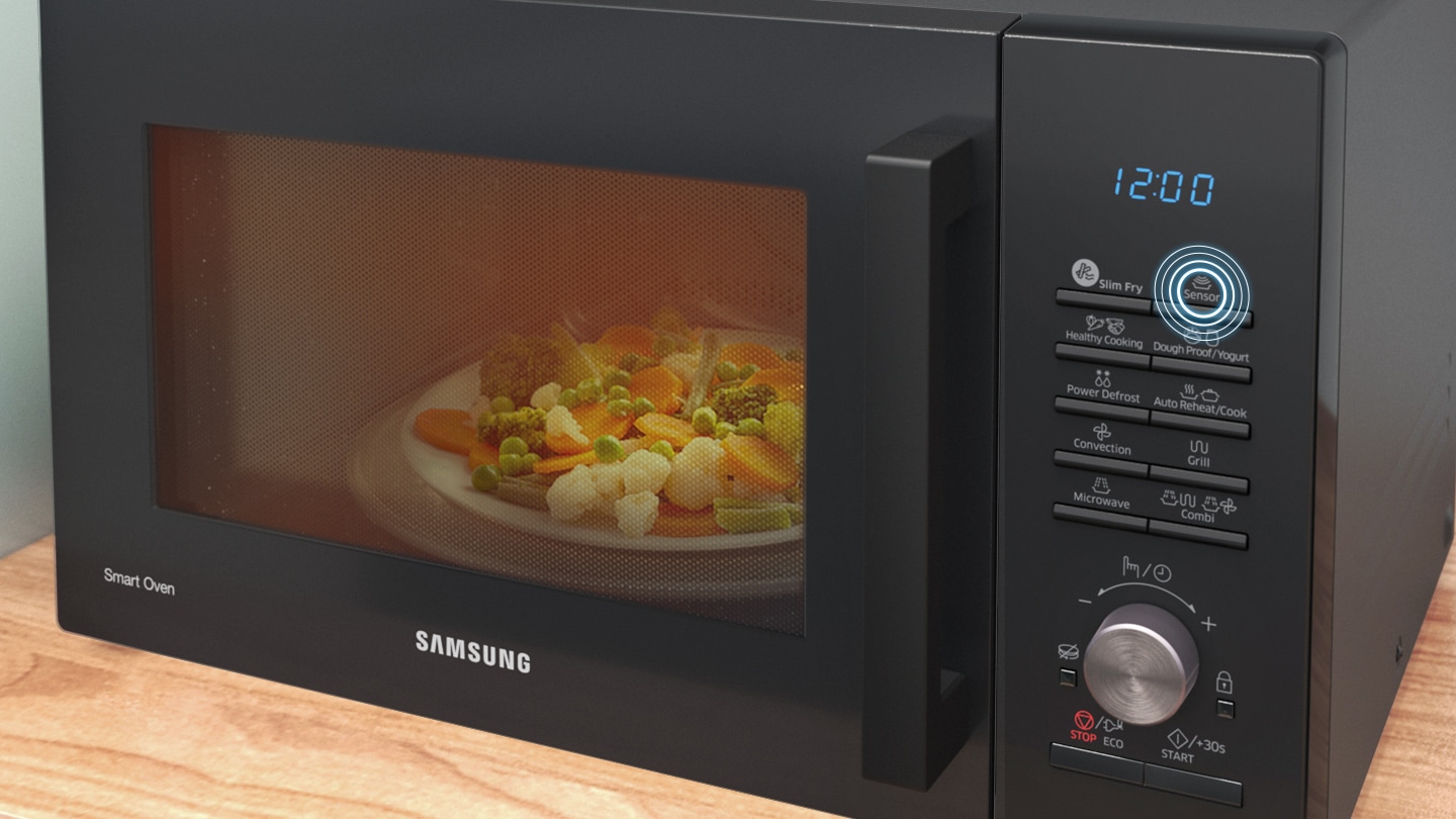 shows the front of the microwave oven with a plate of vegetables being cooked inside. the position of the †sensor cook' button on the control panel is highlighted.