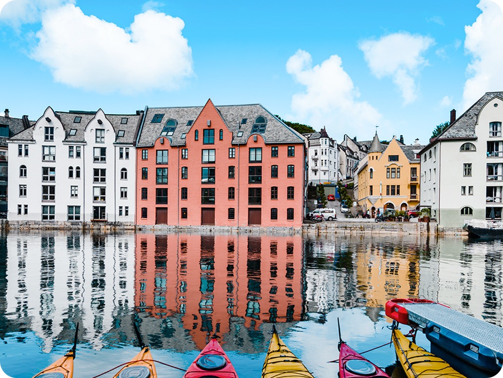 Wide angle icon activated, the shot includes only the tip of the canoes and a portion of the buildings. wide angle are above a landscape of yellow and red canoes lined up in a pier with white and red buildings in the far background.