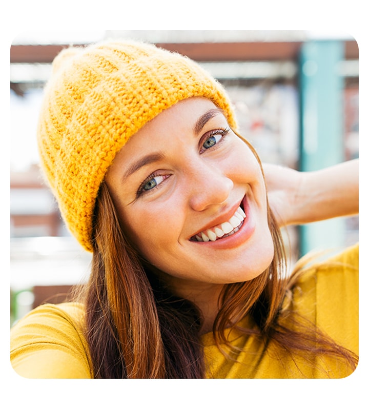 A woman looking into the camera, taking a selfie. The background is subtly blurred out with the bokeh effect.