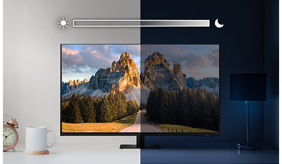 A monitor sits on top of a desk and is split into left and right sides. The left side is brightly lit while the right side is very dark. Above the screen is a slider icon with a sun on the left and a moon on the right.