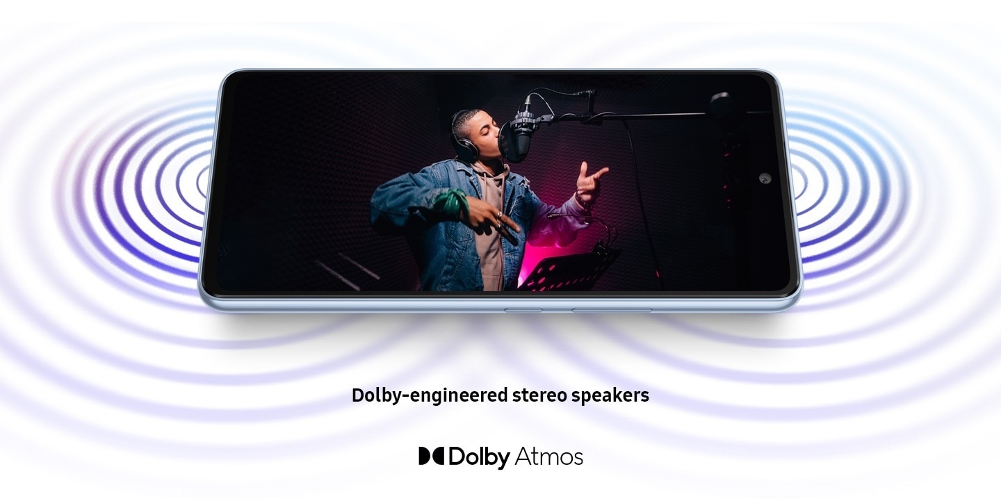 galaxy a53 5g is laid horizontally and shows sound coming from both ends of the device. on screen, a male artist wearing headphones is singing into a studio microphone in a recording session. the dolby atmos logo is shown below.
