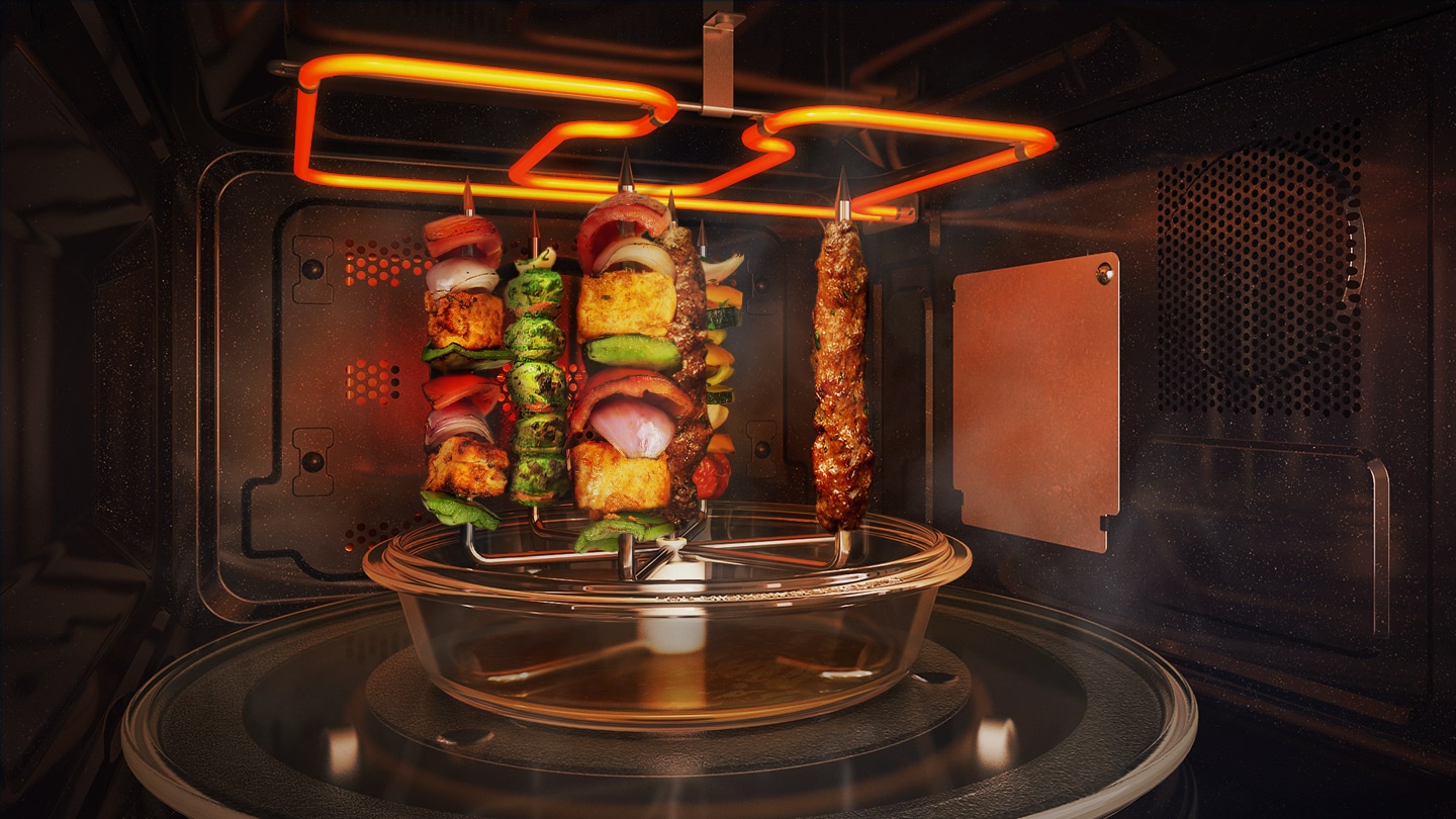 Shows the inside of the microwave oven with the Multi Spit below the Wide Grill. A variety of vegetable and meat kebabs are being cooked on the 6 kebab skewers. A glass plate is underneath the skewers to capture any fat or juice that drips down.