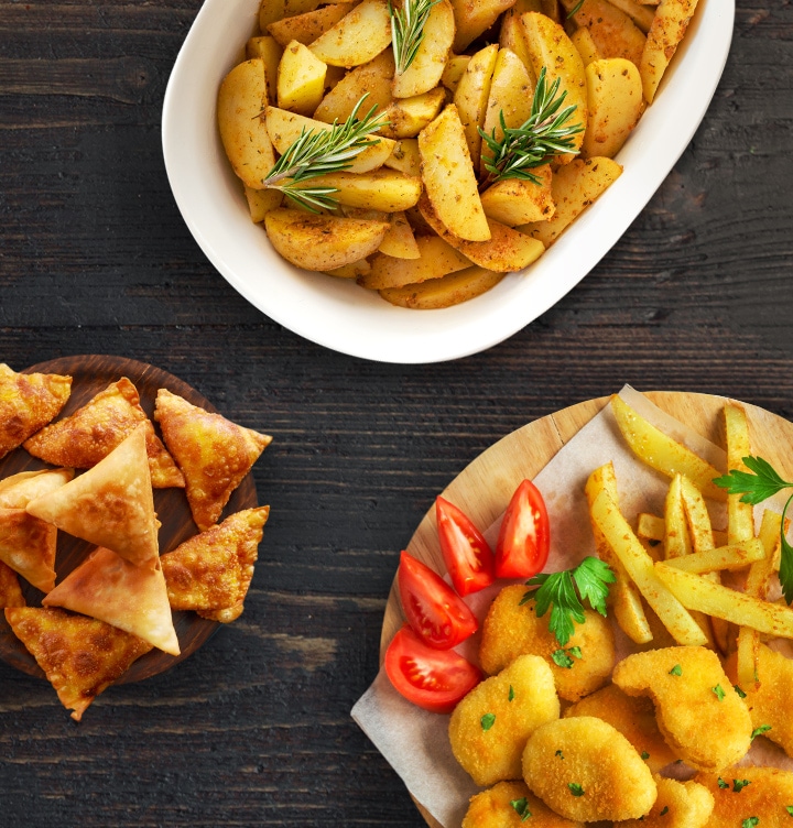 shows a selection of different foods, including potato wedges, chicken nuggets with french fries and samosas, that have been fried in a small amount of oil using slim fry™.