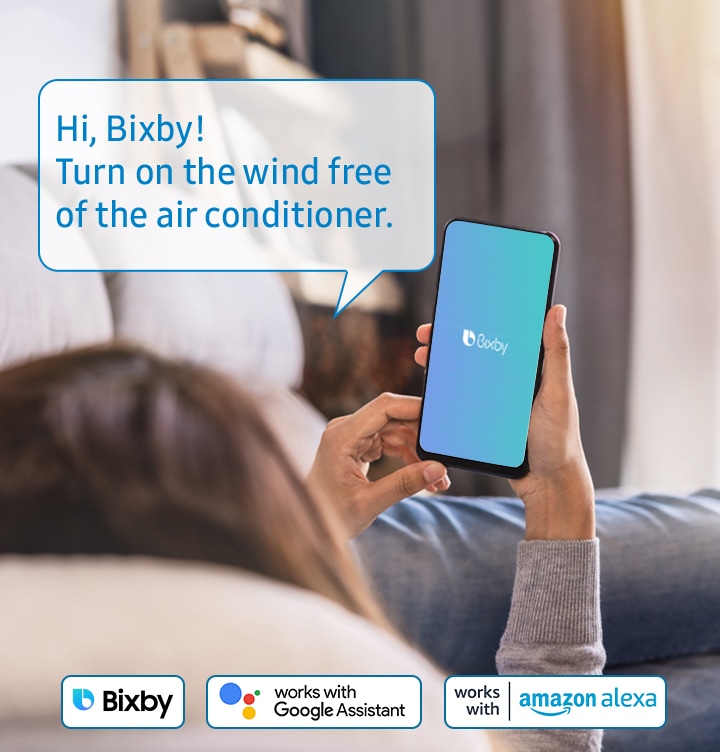 -Shows a person relaxing while controlling the air conditioning with their voice using a voice assistant on their smartphone, such as Samsung Bixby, Amazon Alexa or Google Assistant. The example voice command shown says: &quot"Hi, Bixby! Turn on the wind free of the air conditioner.&quot"