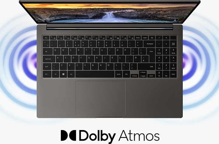 A top view of a graphite Galaxy Book3, open and facing forward with a natural landscape wallpaper onscreen and sound waves coming out of the two speakers. Dolby Atmos logo is shown.