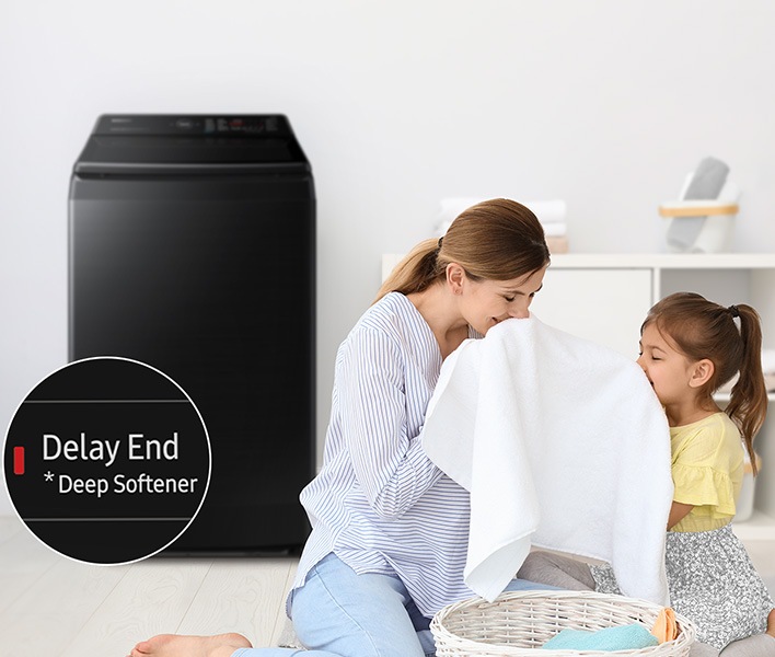 Side of the washing machine, a woman is smelling a towel with her daughter. The towel was washed using the Deep Softenter of the Delay End course.