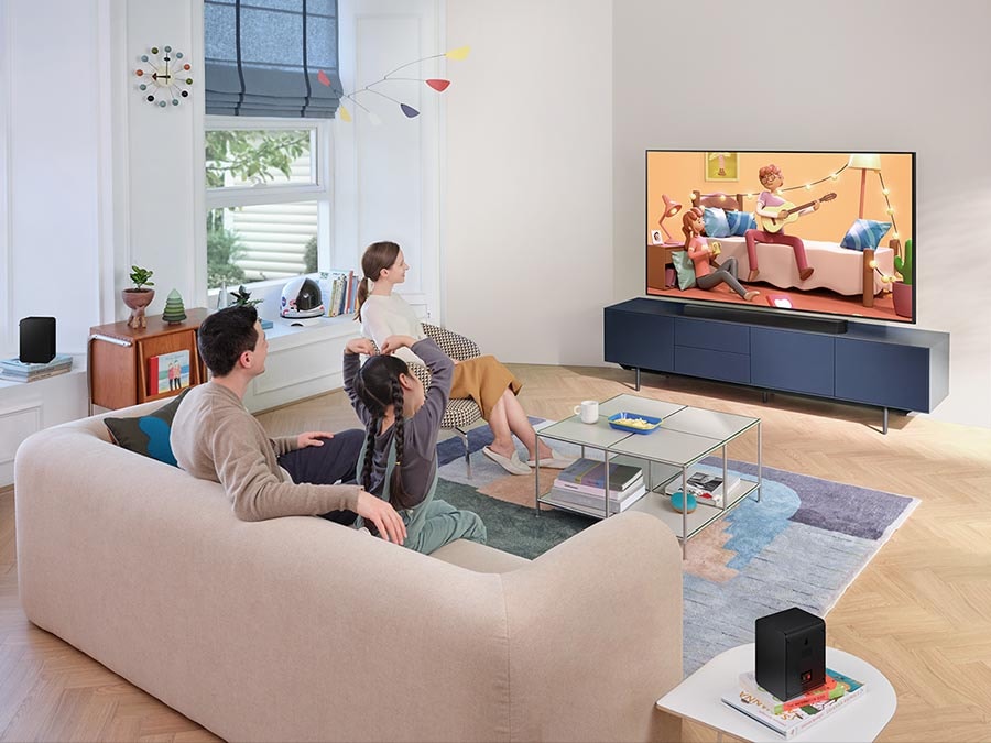 Family watches animation in immersive surround sound with Samsung Wireless Rear Speaker Kit and Soundbar activated together.