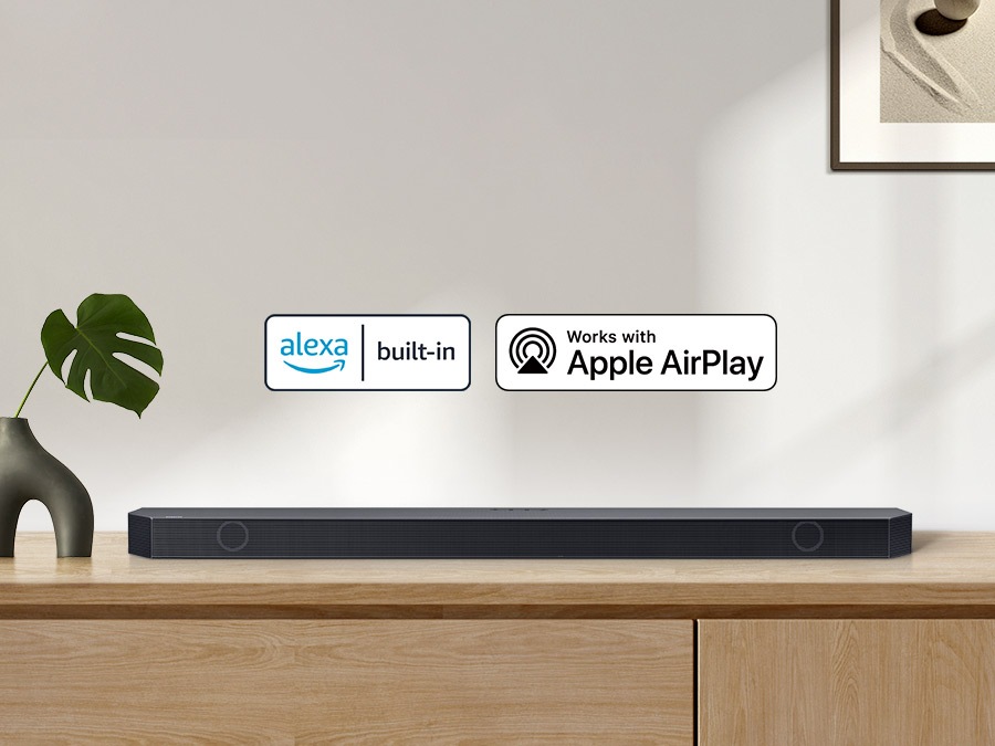 Alexa built-in logo and Works with Apple AirPlay logo with a Samsung Q series Soundbar sitting on top of a cabinet.
