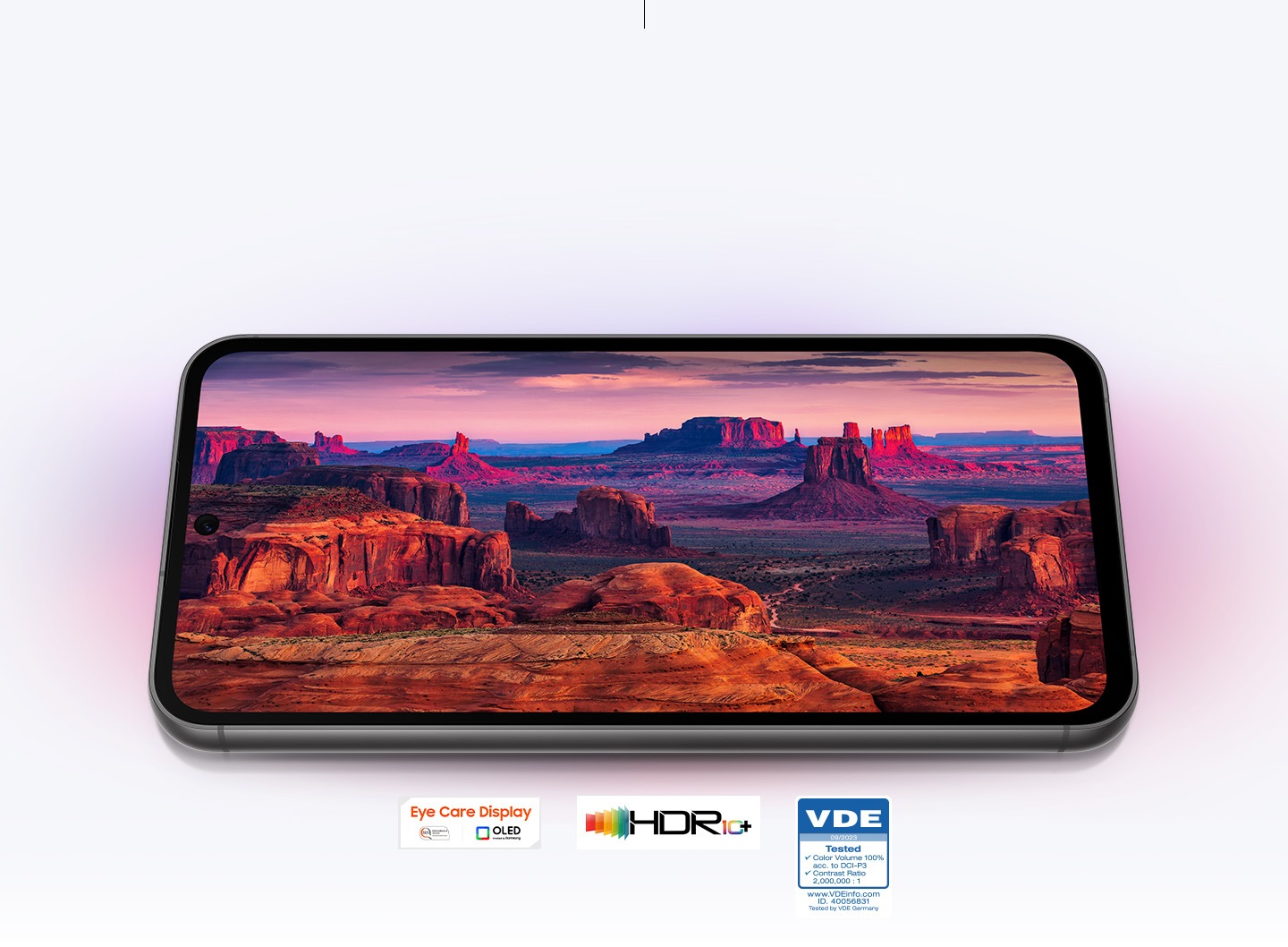 A Galaxy S23 FE device displaying at full screen red and purple mountain landscape captured by its camera. A mark reads Eye Care Display, SGS Performance tested, www.sgs.com/performance, OLED provided by Samsung. HDR10+ Logo. VDE logo with texts 09/2023 Tested Color Volume 100% acc. to DCI-P3 Contrast Ratio 2,000,000:1 www.VDEinfo.com ID. 40056831 Tested by VDE Germany.