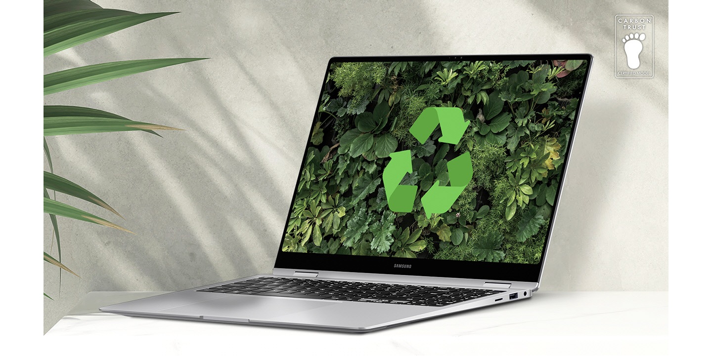 Galaxy Book4 Pro 360 in Platinum Silver placed on a table next to a green plant, open and facing slightly left with a lush greenery wallpaper and recycling logo shown onscreen. Carbon Trust Certification logo with text 'CARBON TRUST. CERTIFIED MODEL.'