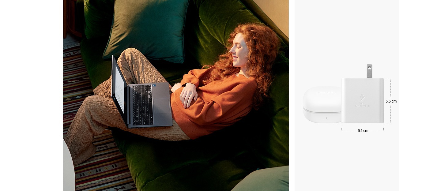 A young woman sitting on a sofa at home is viewing content on Galaxy Book4 in Gray. The light and portable inbox laptop charger is placed next to a Galaxy Buds2 Pro case. The dimensions of the main body of the charger are 4.8 cm horizontally and 5.0 cm vertically.