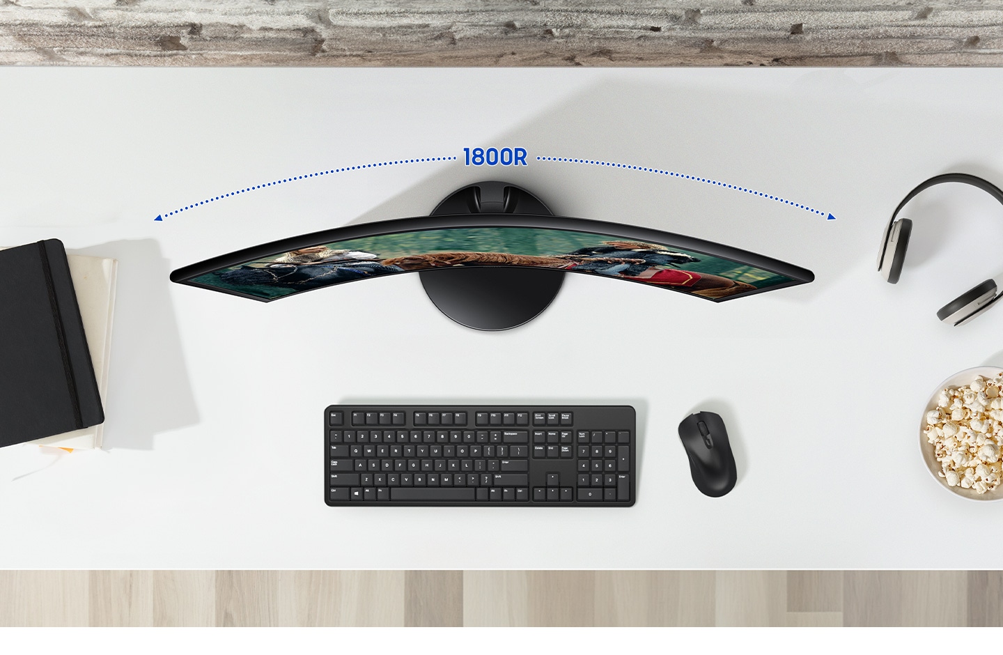 A monitor is on the desk, and there are some peripherals around it. Above the monitor its curvature - 1800R is marked.