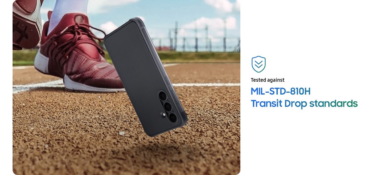 A Galaxy S25 FE encased in the Rugged Case is falling and an inch away from hitting the outdoor track ground to implicate that it's been dropped. A person's feet is visible behind the falling phone. The person is wearing a pair of running shoes. A mark is shown that reads 'Tested against MIL-STD-810H Transit Drop standards'.